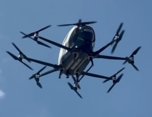 A imagem mostra o carro voador (Ehang 216-S), em seu primeiro voo com a equipe Gohobby. A imagem mostra uma perspectiva do carro aos céus. 